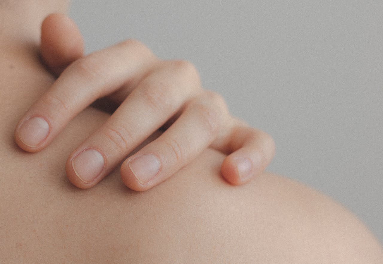 services-01 A gentle close-up of a hand resting on a person's shoulder, emphasizing skin texture.